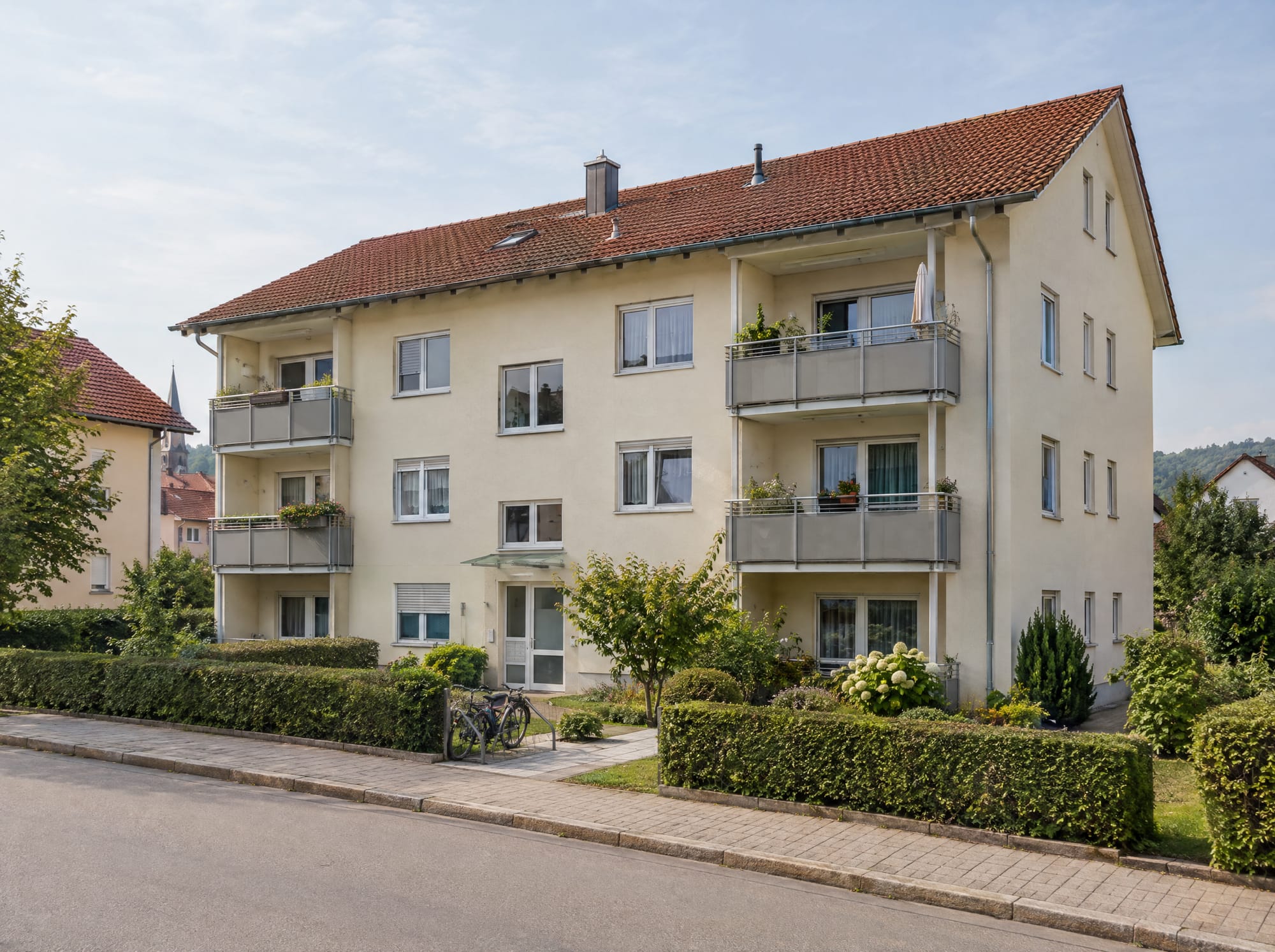 Gepflegtes Mehrfamilienhaus mit Balkonen, Vorgarten und Hecke