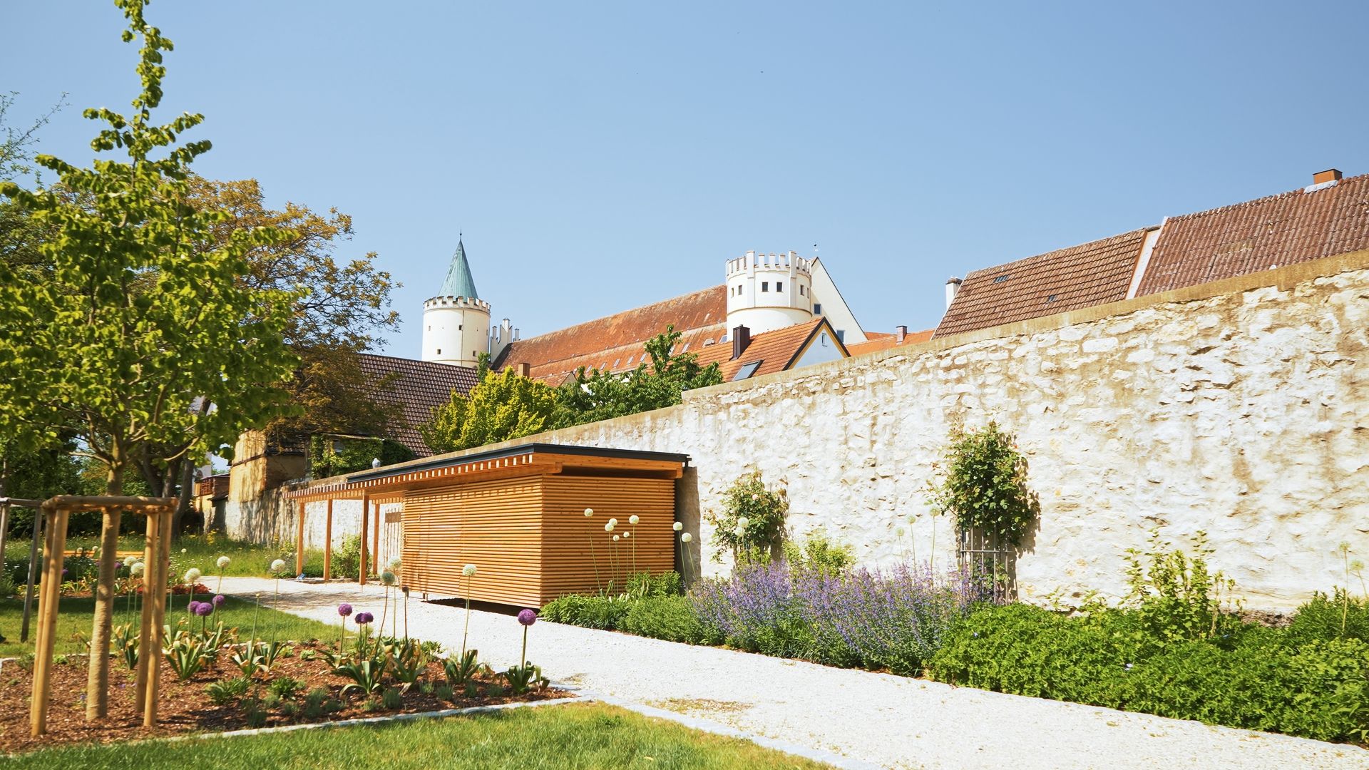 Garten an der historischen Stadtmauer in Lauingen mit Türmen im Hintergrund